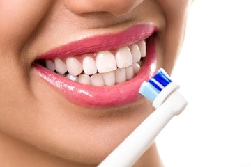 person holding toothbrush up to teeth with a big smile
