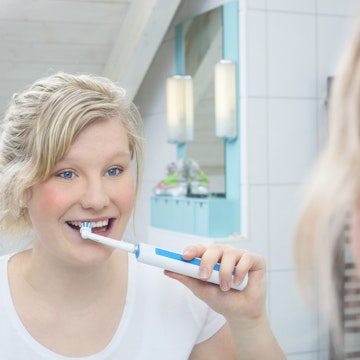 girl brushing teeth in mirror